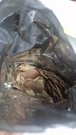 고디바 밀크 초콜릿 포테이토 칩 한 조각을 들고 있는 모습